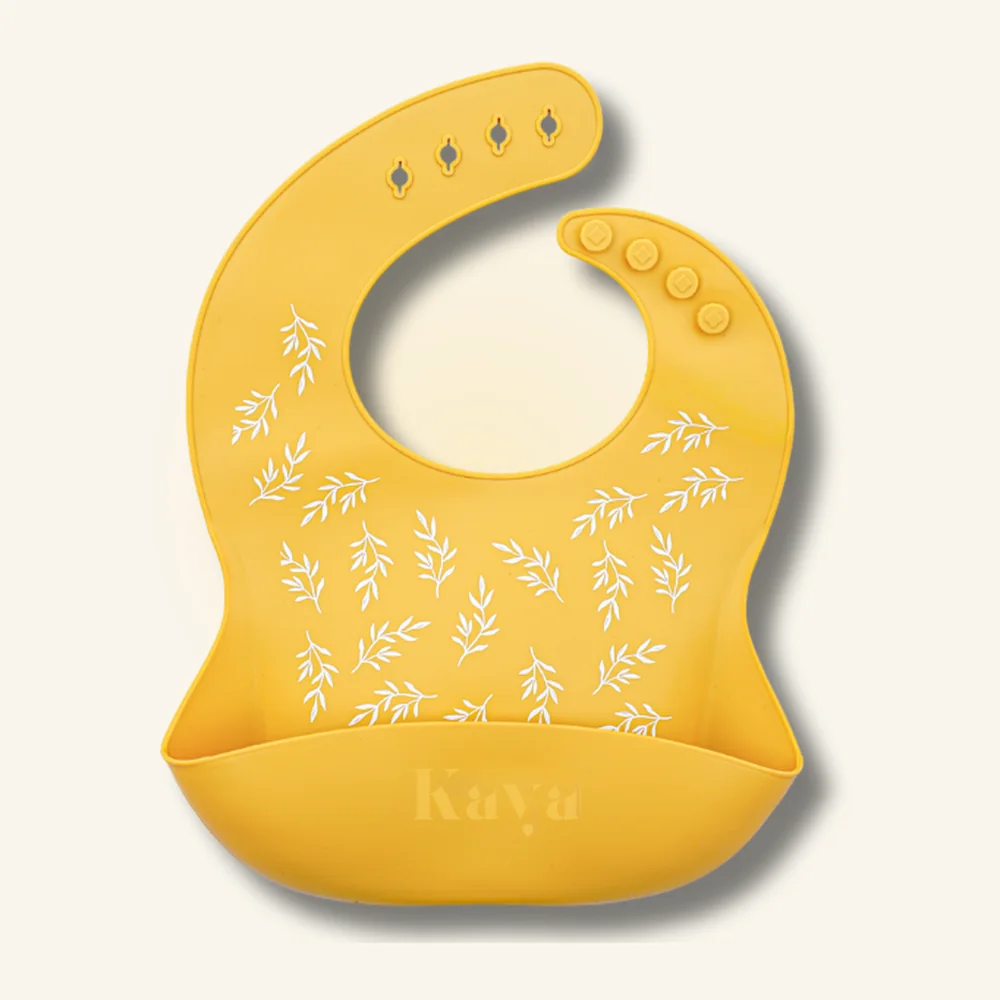 KAYA silicone baby bib in golden yellow with a white leaf print, from the Yellow Pineapple & Leaf 2-pack